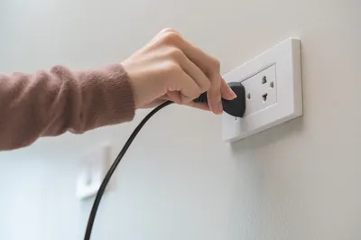 person plugging cord into outlet